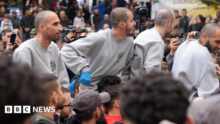 Four freed Palestinian prisoners wearing matching grey sweatshirts are greeted by people after being released from an Israeli jail in Ramallah, in the occupied West Bank.