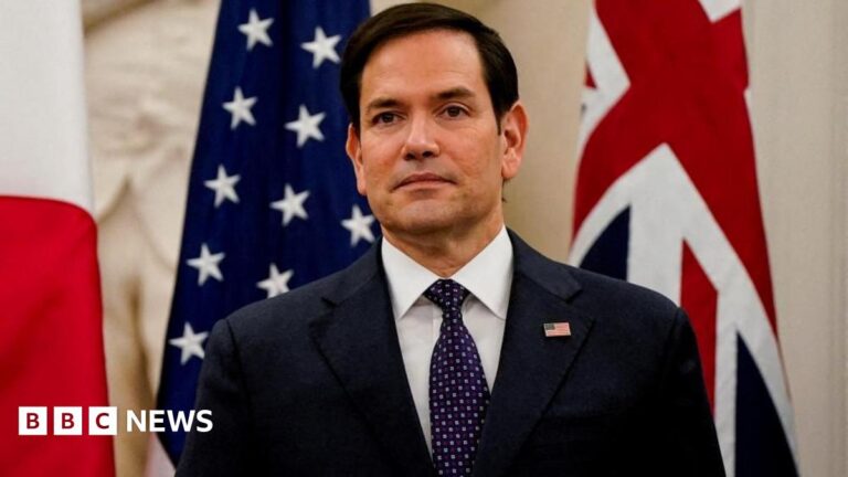 Secretary of State Marco Rubio stands in front of US and UK flags