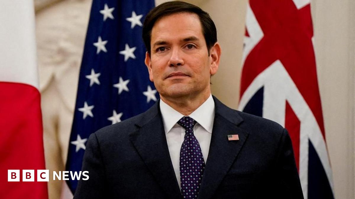 Secretary of State Marco Rubio stands in front of US and UK flags