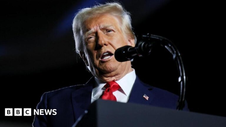 US President Donald Trump is seen standing at a podium behind a microphone