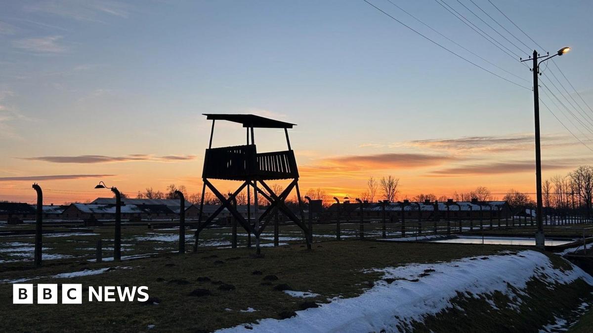 An evening view of Birkenau and a Nazi watchtower as snow lies on the ground