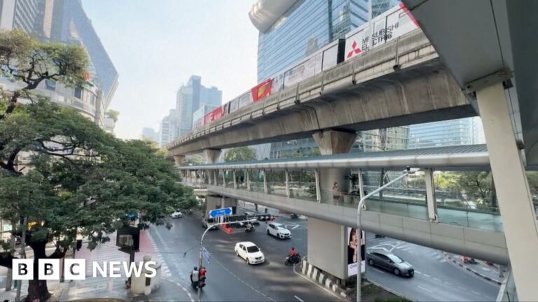 Picture shows a train going past above a busy road in Thailand
