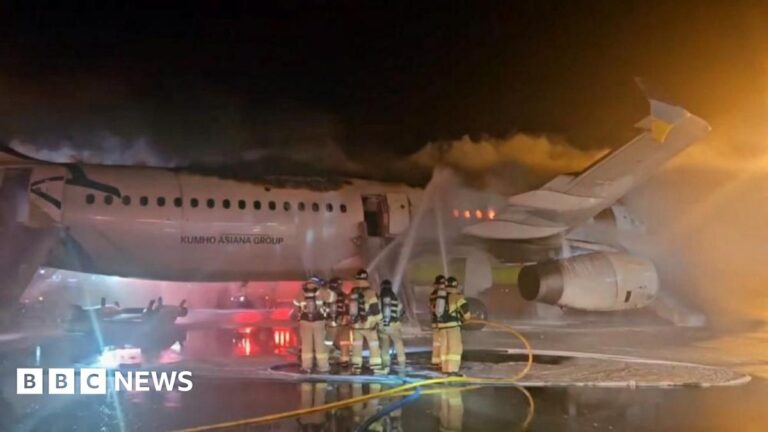 Firefighters tackle a blaze on board an Air Busan aircraft at Gimhae International Airport, South Korea. Picture shows the charred fuselage on the runway with smoke pouring out of it while firefighters standing close to the plane