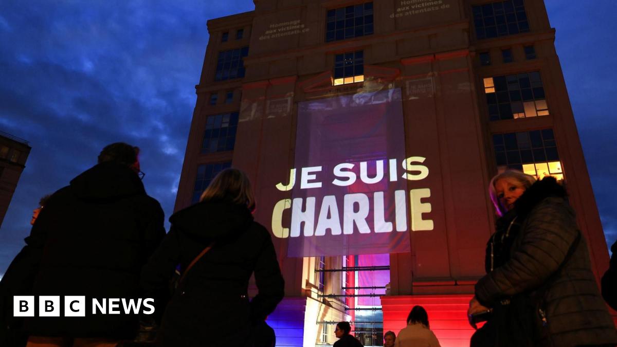 People stand outside a building draped with a banner stating