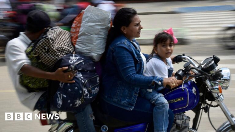 A man, woman and young girl ride a motorcycle through Tibu, Colombia while holding large bags filled with belongings.