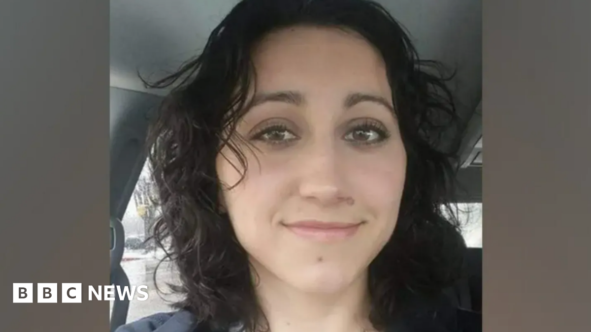 US mother Kimberlee Singler smiles as she poses for a selfie inside a vehicle. She has long wavy black hair and dark eyes.