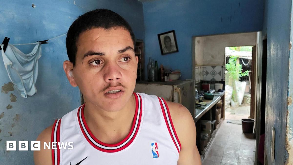 Dariel Cruz García, wearing a white basketball shirt, poses for a photo at his home in Havana, Cuba, after being released from prison