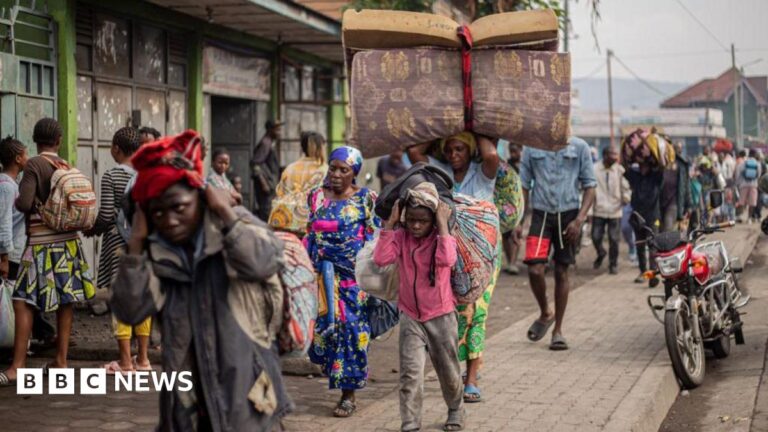 Residents carry their belongings as they flee from Kibati, where fighting has intensified, towards the city of Goma on January 26, 2025.
