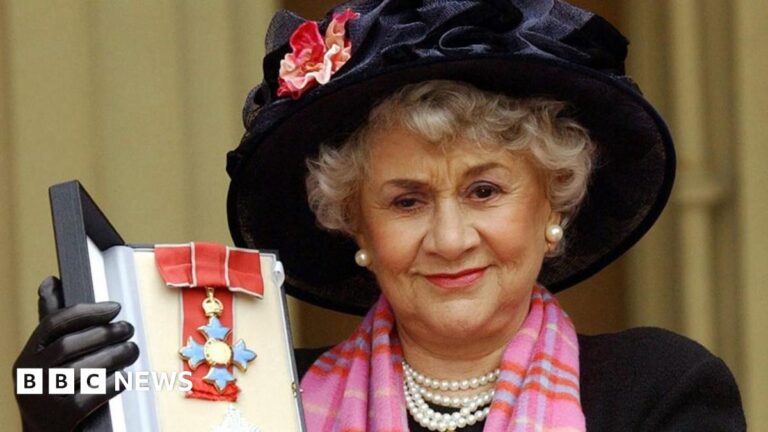 Dame Joan Plowright holding up her medal after being made a dame in 2004