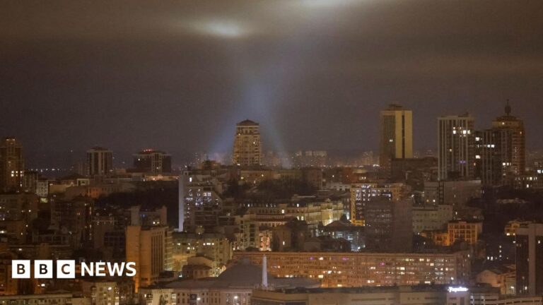 Ukrainian service personnel use searchlights as they search for drones in the sky over Kyiv during a Russian drone strike, 13 January