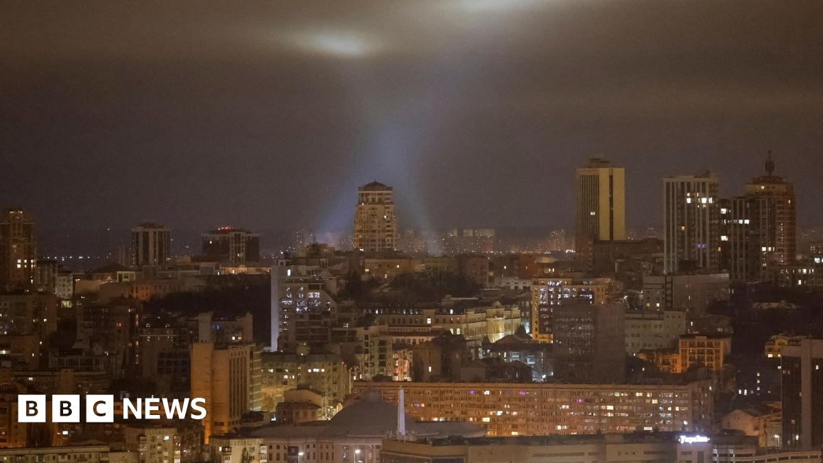 Ukrainian service personnel use searchlights as they search for drones in the sky over Kyiv during a Russian drone strike, 13 January