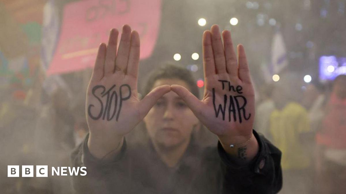 Woman protesting against the government and showing support for the 7 October hostages holds up both hands, with the words