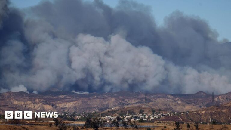 Smoke plumes can be seen billowing in the sky near communities in Los Angeles county