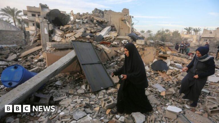 Two Palestinian women search and collect usable items among the rubble of a completely destroyed house in Gaza.