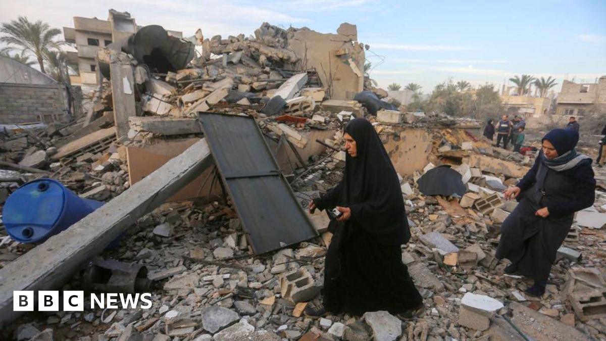 Two Palestinian women search and collect usable items among the rubble of a completely destroyed house in Gaza.