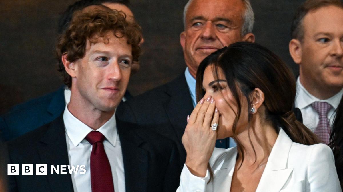 Lauren Sanchez whispering to Mark Zuckerberg, who is smiling - Zuckerberg is wearing a suit, and Ms Sanchez has a white blouse on