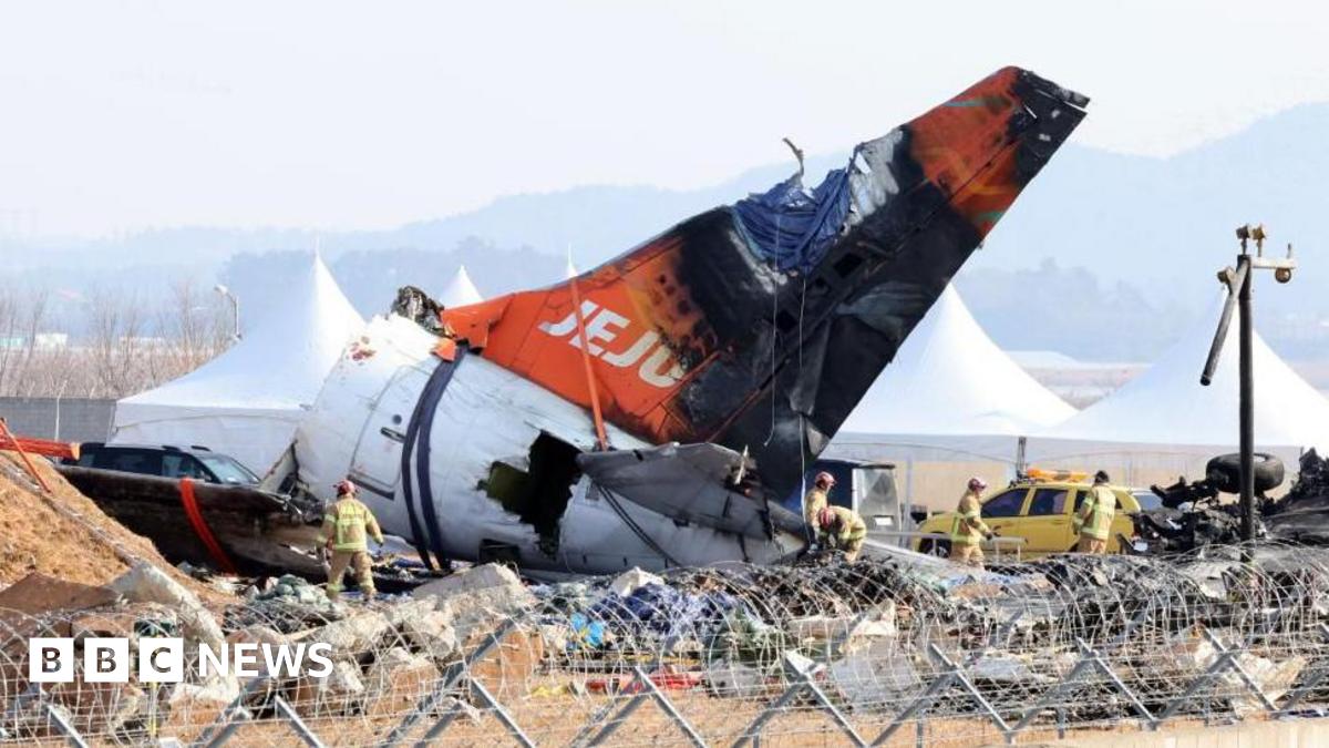 Firefighters remove tarpaulin sheets covering the debris of a Jeju Air passenger plane at Muan International Airport in Muan, southwestern South Korea, 13 January 2025, following its crash on 29 December 2024.