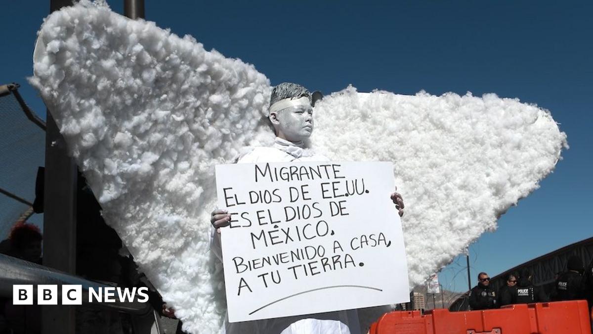 A member of a religious group dressed as an angel takes part in a demonstration at the Ciudad Juarez international crossing from Mexico to the US. They hold up a sign written in Spanish protesting against the the immigration policies of Donald Trump. It reads