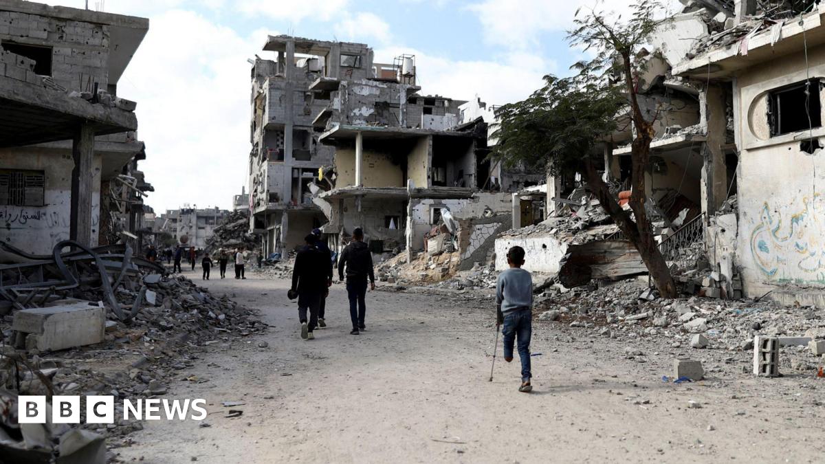 An aerial view taken with a drone shows internally displaced Palestinians walking along a street among the grey, dusty rubble of destroyed buildings in Rafah