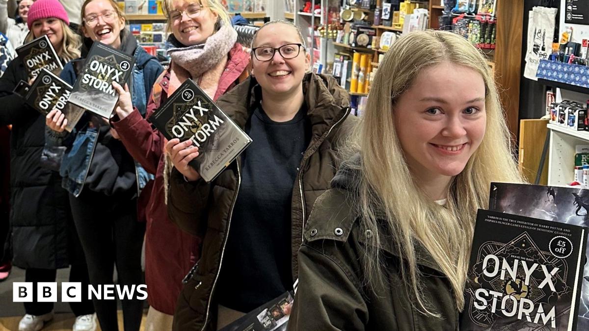 Young women queue up to buy copies of Onyx Storm in Waterstones in Warrington, holding up their books