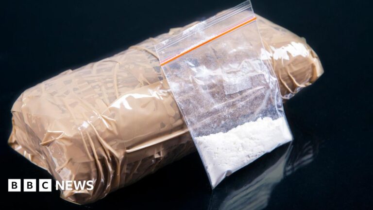 A small plastic bag containing a white powder next to a package wrapped in brown parcel tape.