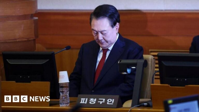 South Korean Yoon Suk Yeol looking downwards while sitting in the dock in a courtroom
