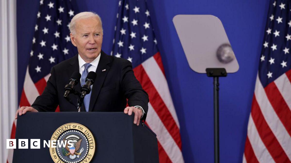 Joe Biden speaks at a lectern in front of two US flags