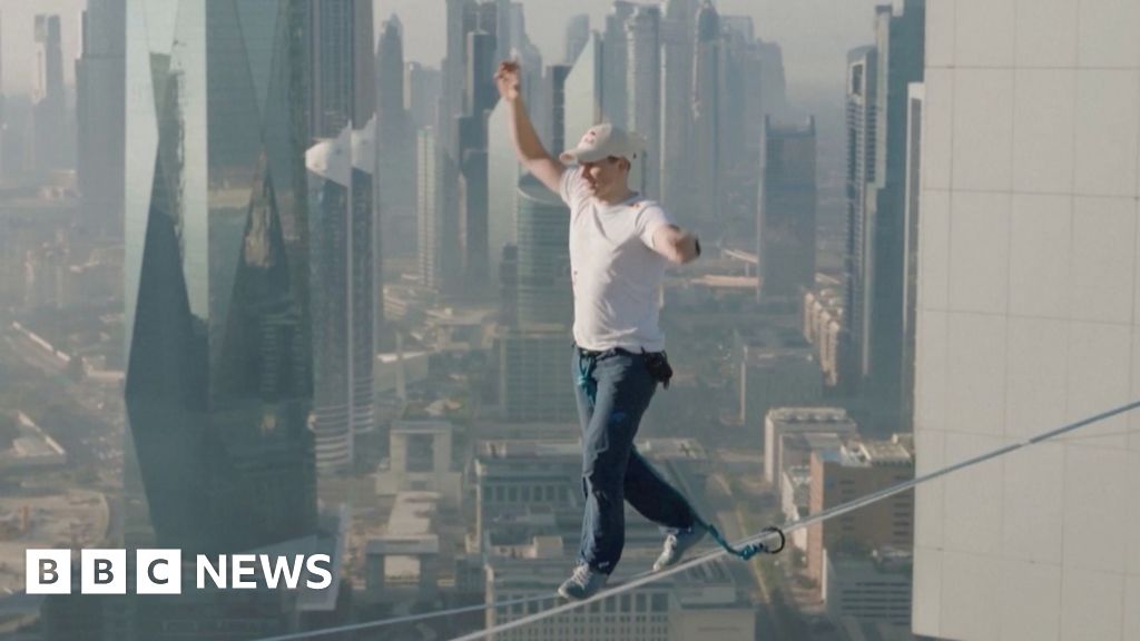 Man balancing on highline with Dubai skyline in the background