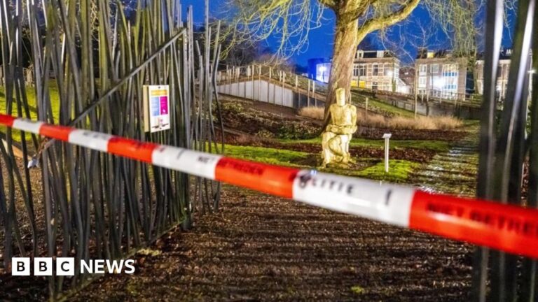 Red and white police tape crosses a gate before a statue in front of a tree outside Drents Museum in Assen, the Netherlands