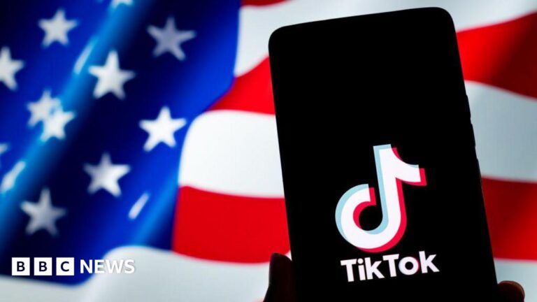 A TikTok logo is displayed on a smartphone with the U.S. flag in the background