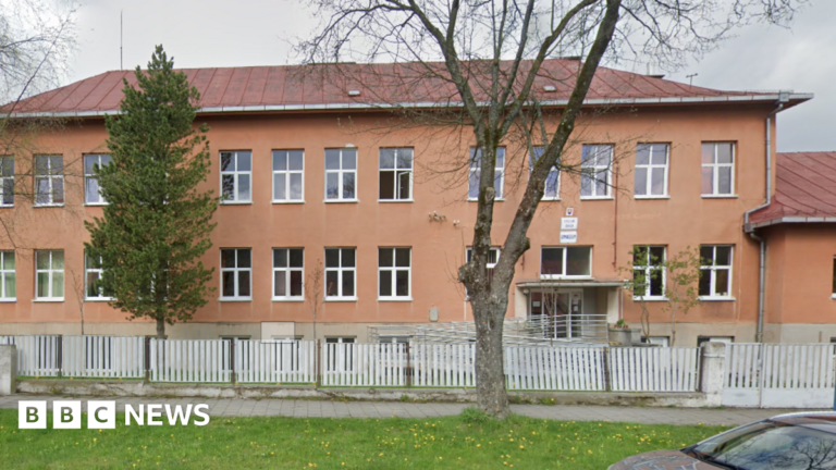 An orange-coloured school building with two trees in front of it